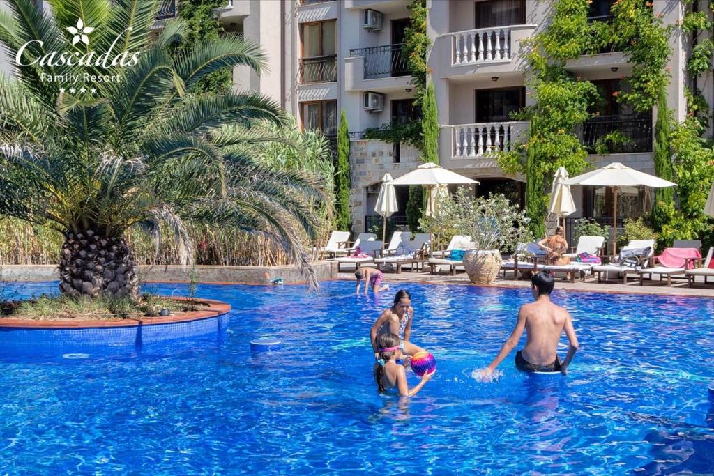 Peldbaseins ar palmām un viesiem, kas izbauda ūdens priekus, ģimenes atpūtas kompleksā. Apkārt baseinam ir sauļošanās krēsli un saulessargi, radot relaksējošu atmosfēru.