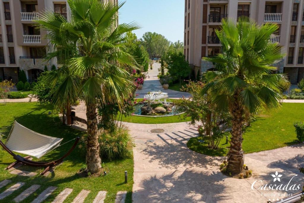 Viegla ainava ar palmu kokiem, šūpuļtīklu un dārzu, kas ved uz ūdens strūklaku un viesnīcu. Ideāla atpūtas vieta ģimenēm.