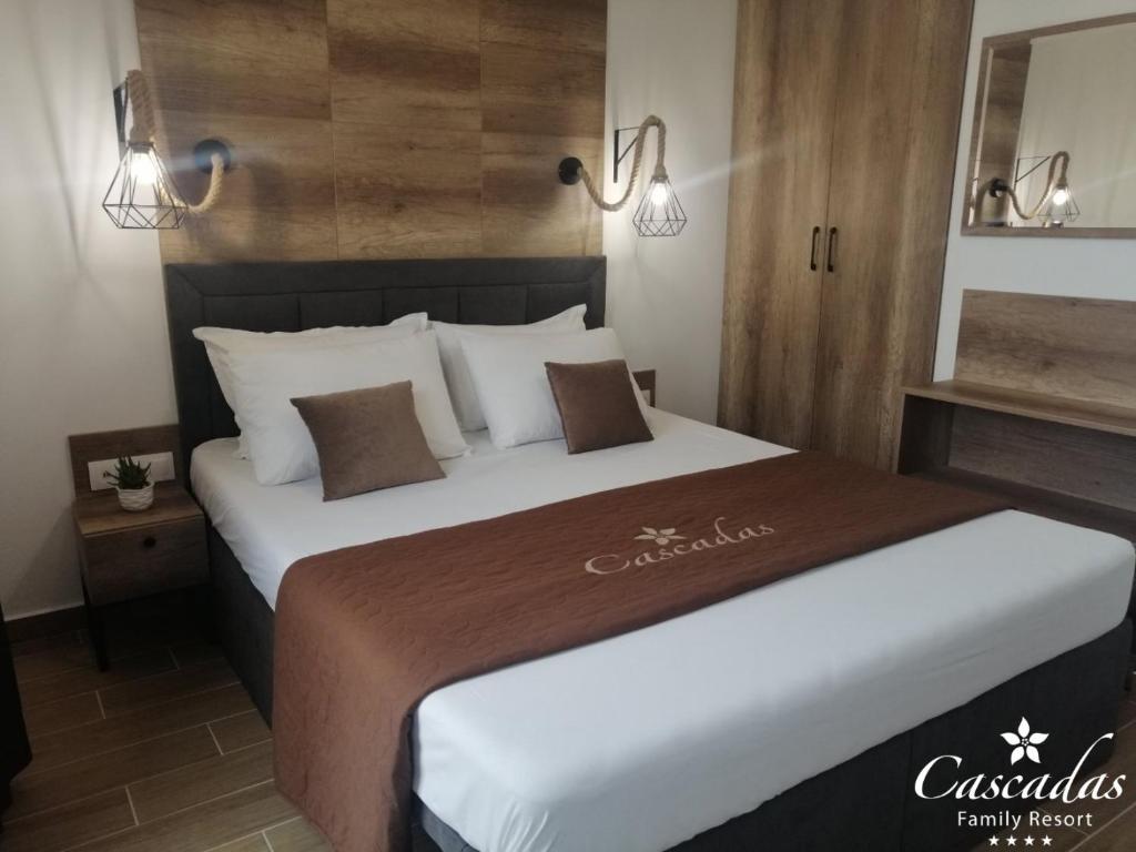 Mūsdienīga viesnīcas numura iekārtojums ar ērtu gultu, dekoratīvām spilveniem un koka elementiem. Numurā ir gaismas ķermeņi un neliela naktsgaldiņa ar augiem.