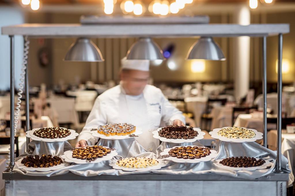 Šefpavārs izkārtojis dažādas šokolādes konfektes uz galda restorānā, radot pievilcīgu desertu izvēli, kas ir paredzēta viesu apkalpošanai.