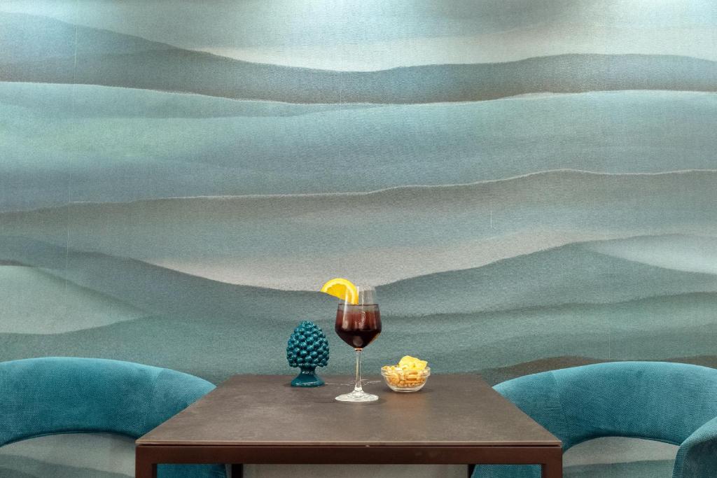 Kafijas galds ar dzērienu un uzkodām, fona viļņainā sienas apdare radījusi relaksējošu atmosfēru. Tur ir arī dekoratīvs objekts un krāsainas krēsli.