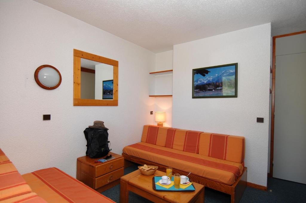 Mūsdienīga viesnīcas istaba ar divām dīvāngultām, koka galdiņu un krēslu, kā arī dekoratīvu mākslas darbu uz sienas. Uz galda atrodas brokastu komplekts ar dzērieniem un uzkodām.