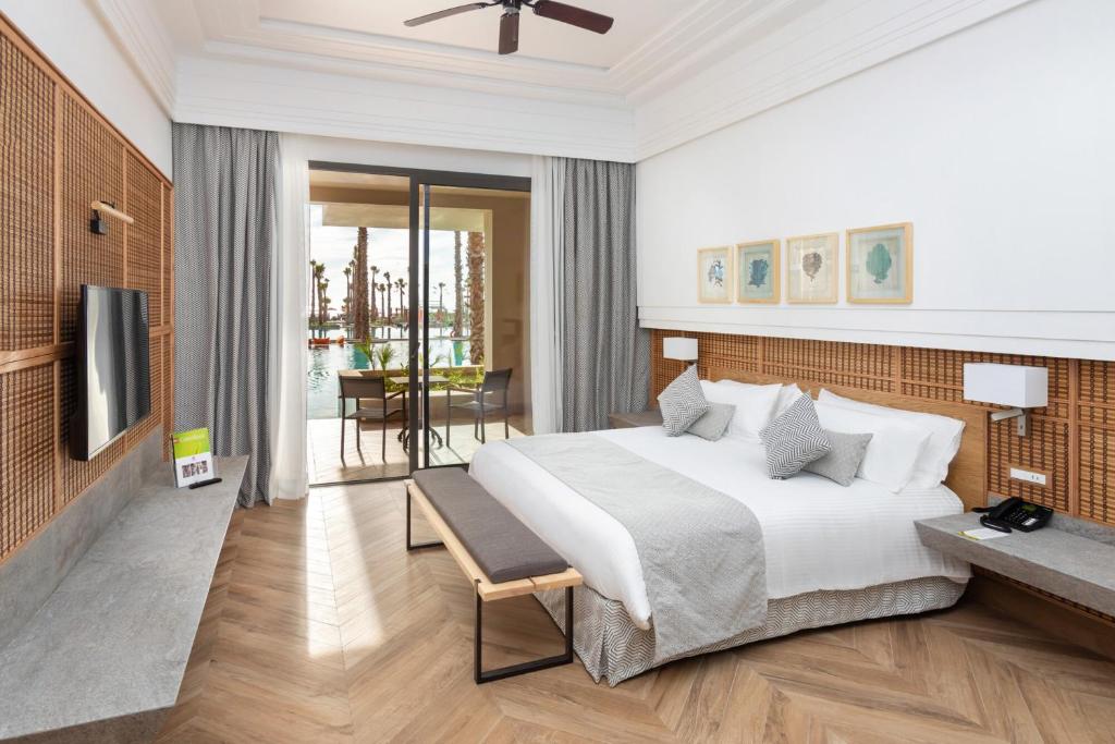 Mūsdienīgs viesnīcas numurs ar plašu gultu, televizoru un skatu uz baseinu. Interjers ir gaišs un elegants, ar koka elementiem un dabīgām krāsām.