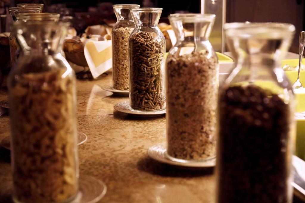 Skaisti uzglabāšanas trauki ar graudiem un riekstiem, izvietoti uz galda, radot pievilcīgu un sakārtotu izskatu. Ideāli piemēroti brokastu vai uzkodu stacijai.