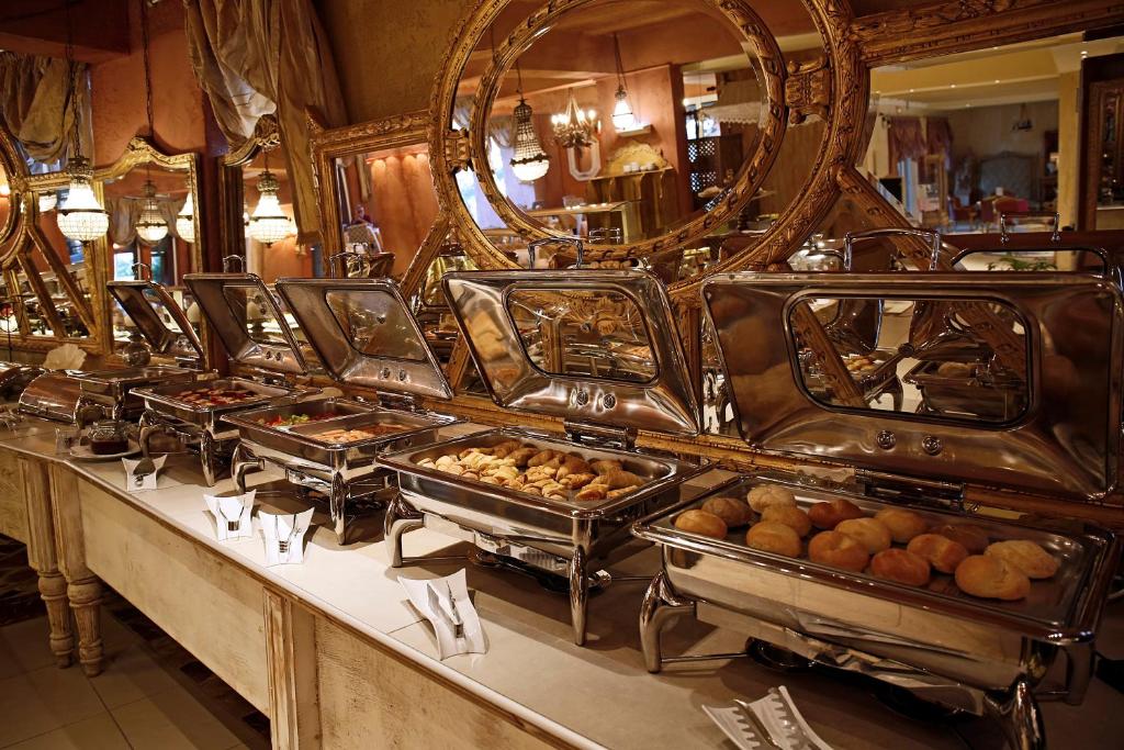 Skaisti noformēts bufete ar dažādiem ēdieniem, tostarp konditorejas izstrādājumiem un maizītēm, atspoguļojas eleganti dekorētā telpā.
