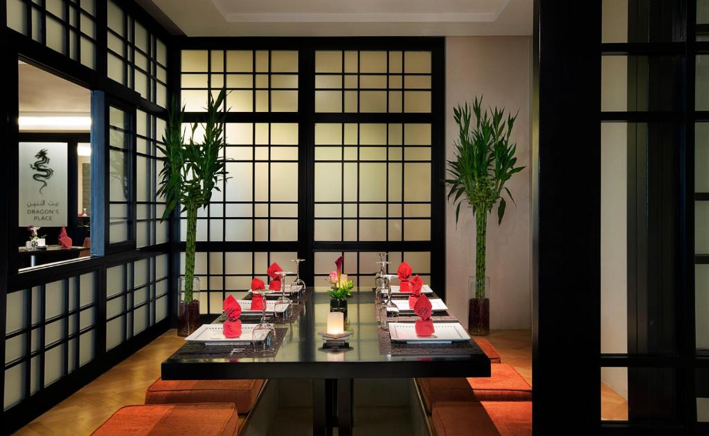 Viesnīcas Bahi Ajman Palace restorāns ar stilīgu galdu un dekoratīvām puķēm.