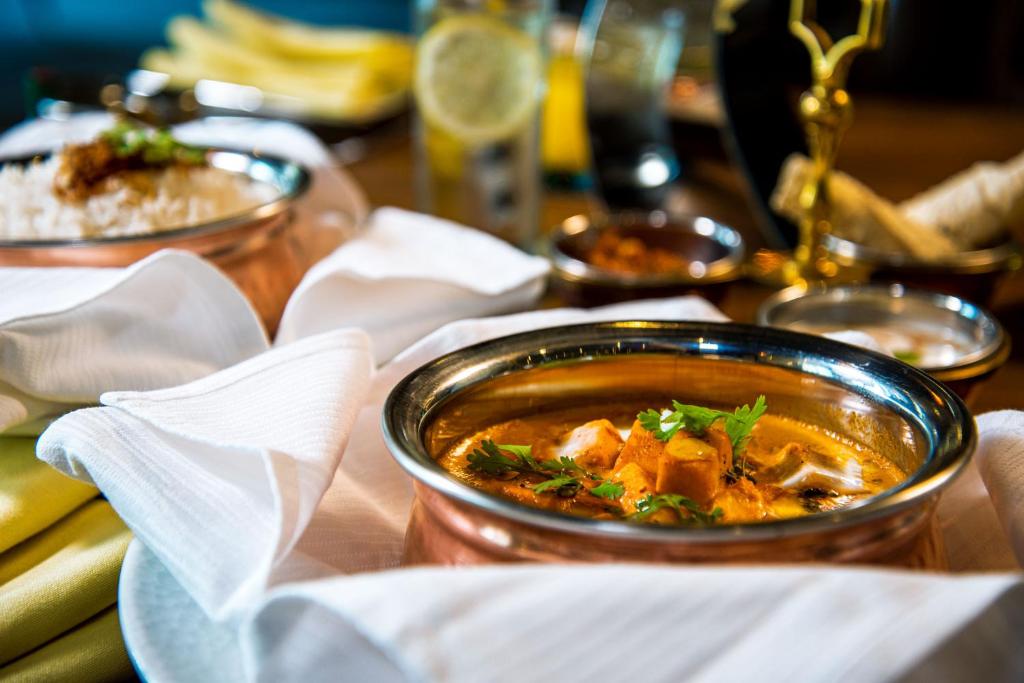 Indiešu ēdiens ar garšīgu mērci un svaigiem koriandra lapām, pasniegts ar balto rīsu un citiem ēdieniem.