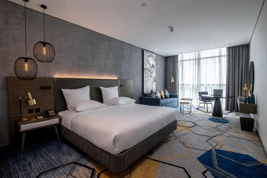 Mūsdienīgs viesnīcas numurs ar divguļamo gultu, dīvānu un darba galdu, apgaismots ar stilīgām lampām. Numurā ir lieli logi, kas piedāvā dabisko apgaismojumu un patīkamu interjeru.