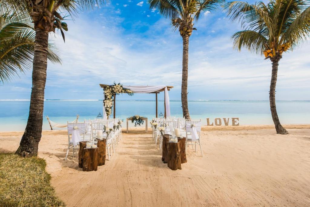 Romantiska kāzu ceremonija piekrastē LUX* Le Morne, palmām un mīlestības zīmi.