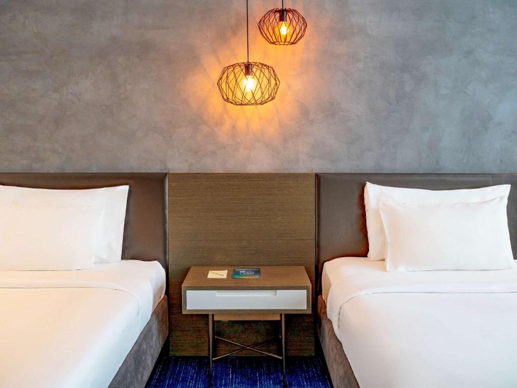 Mūsdienīgs guļamistabas interjers ar divām vienvietīgām gultām, stilīgu naktsgaldiņu un dekoratīvām lampām. Siltas krāsas un minimālisma dizains rada komfortablu atmosfēru.