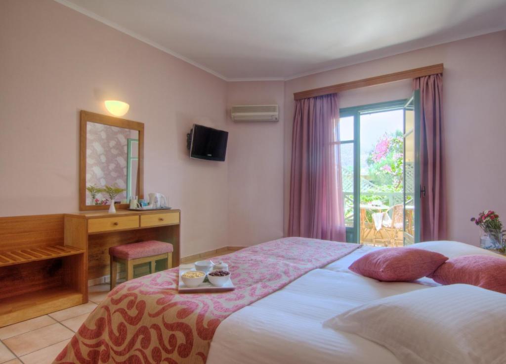 Mūsdienīga viesnīcas istaba ar divām gultām, dekora elementiem un skatu uz terasi. Telpā ir rakstāmgalds, televizors un gaismas avots, radot mājīgu atmosfēru.