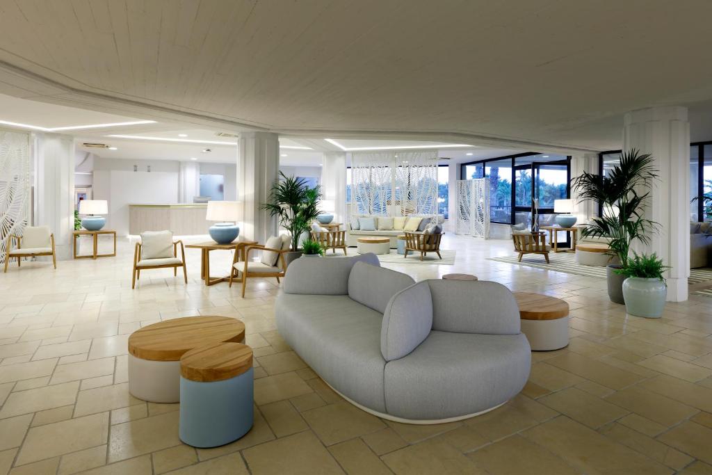 Mūsdienīgs viesnīcas interjers ar plašu atpūtas zonu, elegantiem mēbeļu komplektiem un zaļām augiem. Gaismas un neitrālas krāsas rada mierīgu atmosfēru.