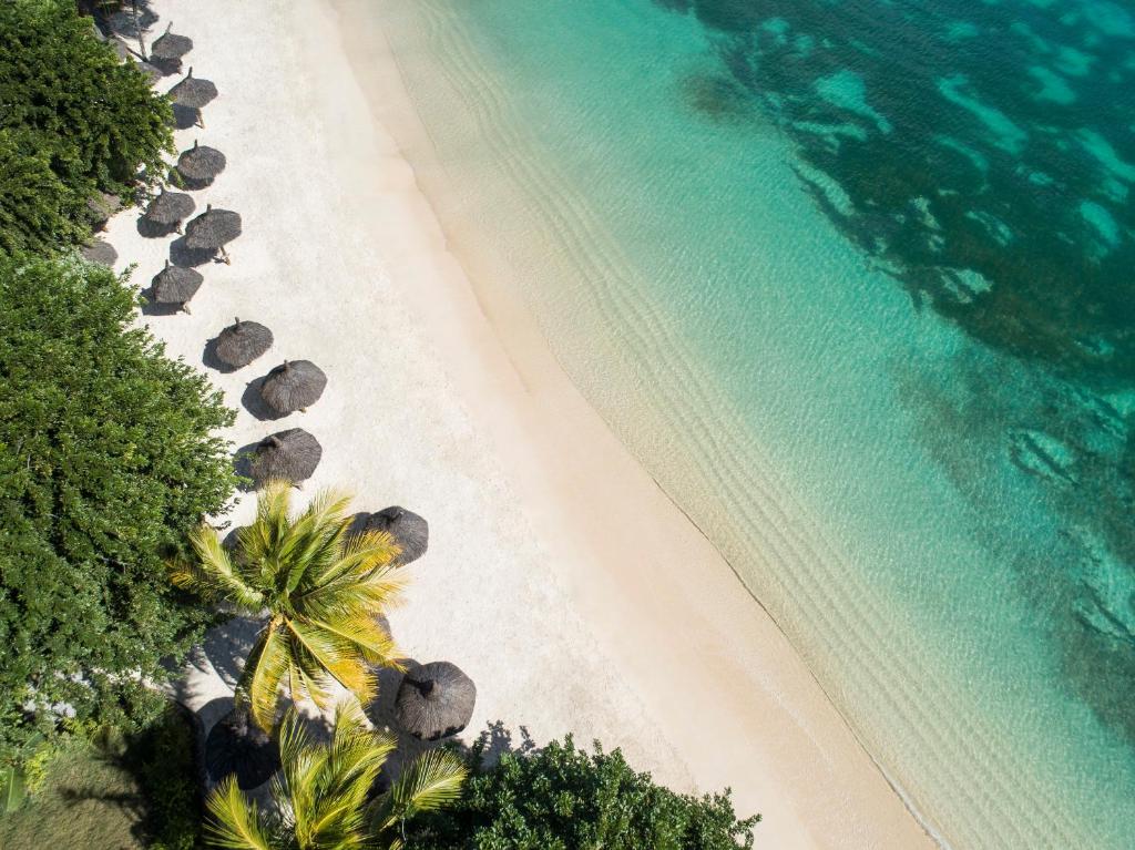 LUX* Grand Baie pludmale ar palmām un sauļošanās krēsliem piekrastē