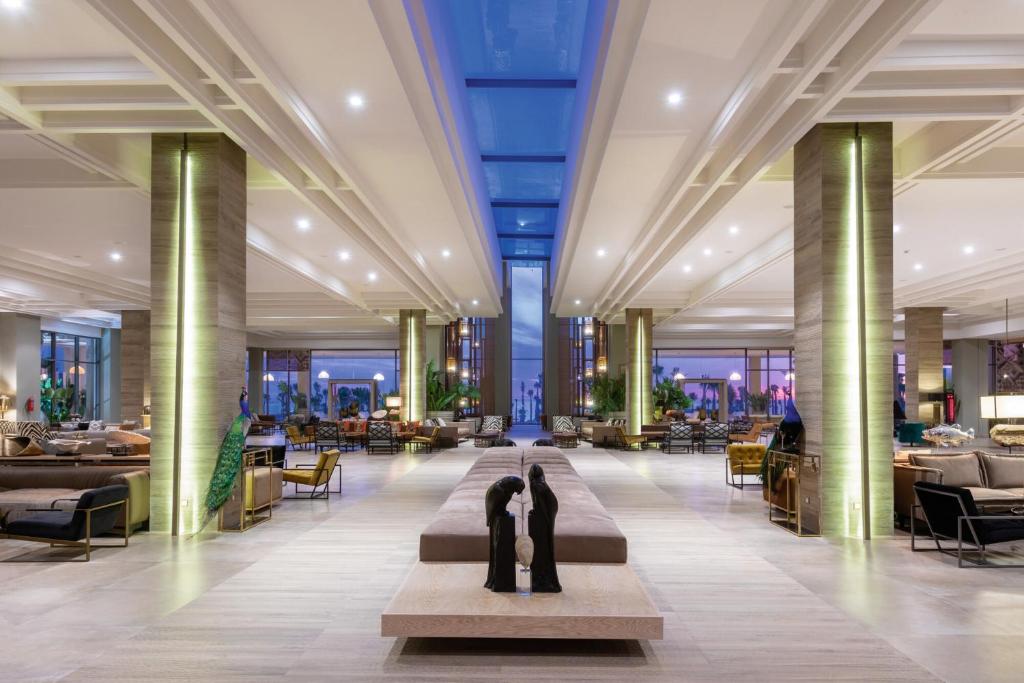 Mūsdienīgs viesnīcas vestibils ar plašu telpu, stilīgu mēbeļu izkārtojumu un dabisku apgaismojumu, kas veido patīkamu un elegantu atmosfēru.