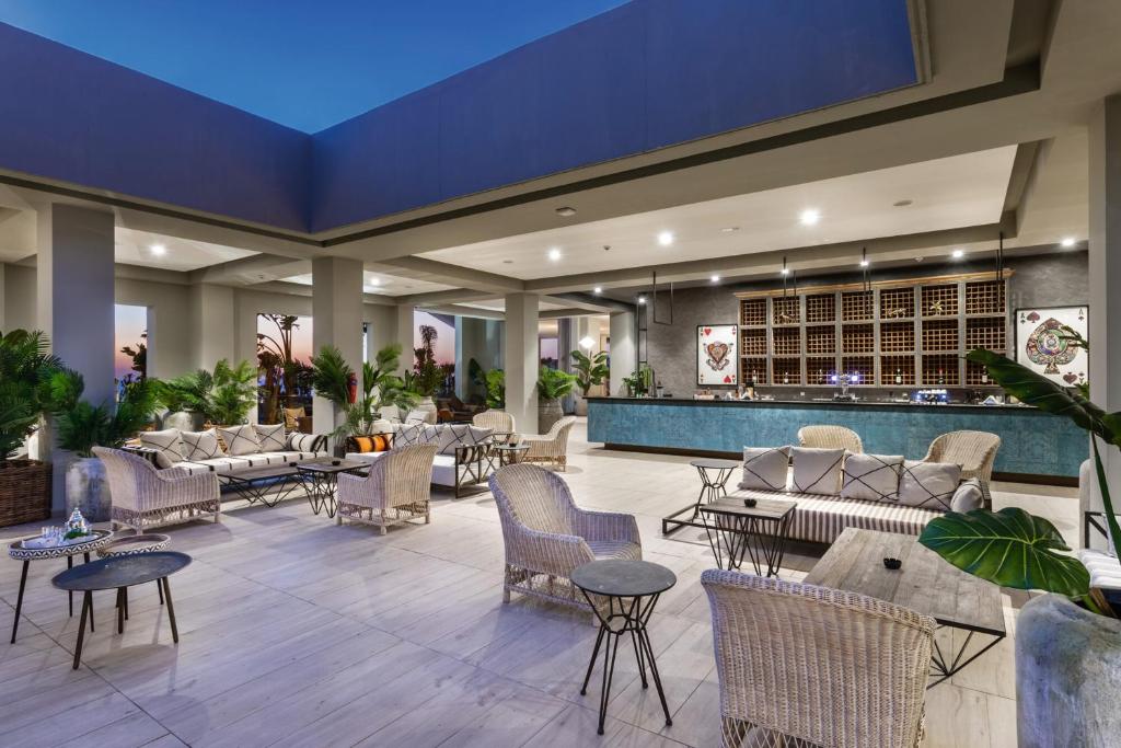 Mūsdienīgs un elegants atpūtas telpas interjers ar ērtiem krēsliem, galdiem un bāru, apzaļumots ar augiem, ideāli piemērots relaksācijai un sociālām aktivitātēm.