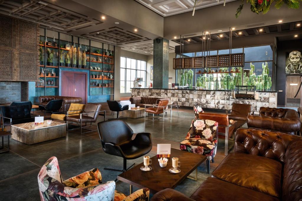 Mūsdienīgs un stilīgs viesnīcas bārs ar plašu sēdvietu izvēli, elegantu apgaismojumu un dekoratīvām augu kompozīcijām. Interjers apvieno komfortu un estētiku, radot lielisku atmosfēru relaksācijai.