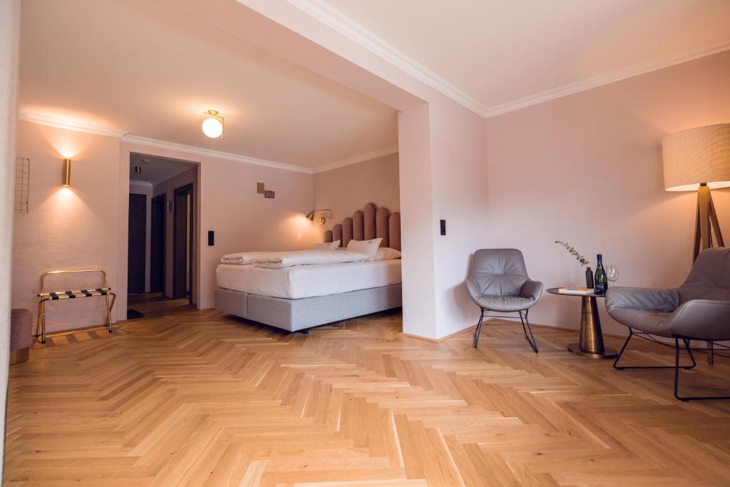 Mūsdienīgs viesnīcas numurs ar ērtu gultu, divām krēslām un elegantu apgaismojumu, kas rada relaksējošu atmosfēru. Koka grīda piešķir siltumu un eleganci interjeram.