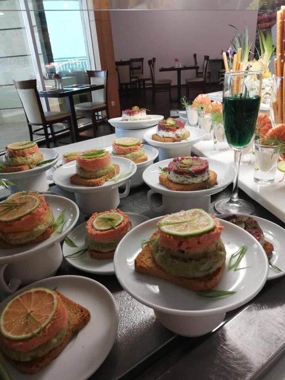 Gatavošanas galds ar krāšņu ēdienu prezentāciju, kas ietver dažādas kārtainas uzkodas uz grauzdiņu pamata un dzērienu.