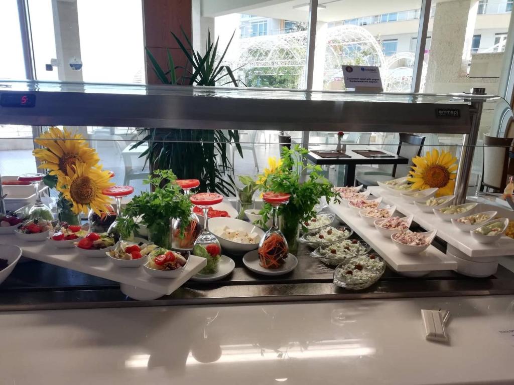 Svaigu salātu bufete ar ziediem un garnējumiem, kas izkārtoti uz baltiem traukiem. Izcila izvēle veselīgām maltītēm.