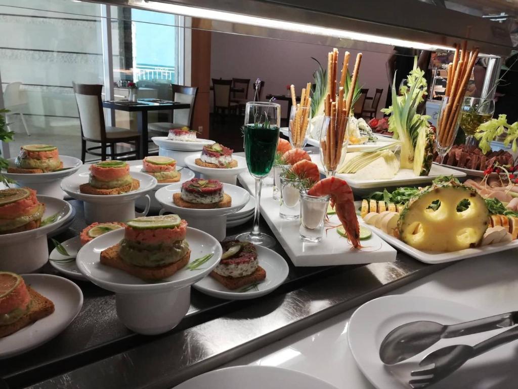 Bagātīgi klātas uzkodas ar dažādiem ēdieniem, tostarp laša un krabju kārtām, garnelēm un augļiem, kas pasniegtas elegantā restorāna stilā.