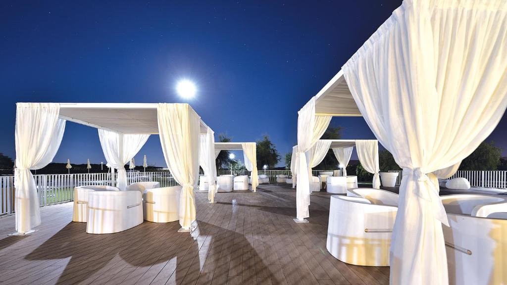 Janna 'e Sole Resort āra atpūtas zona ar baltām nojumēm mēness gaismā.