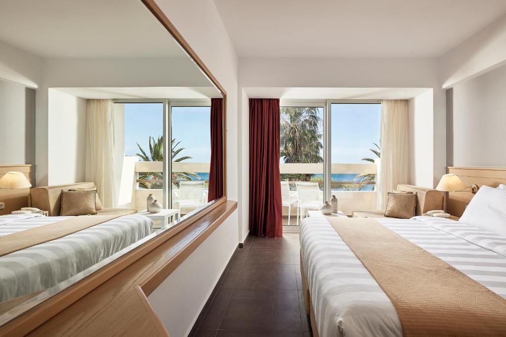 Mūsdienīgs viesnīcas numurs ar lieliem logiem, kas nodrošina skatu uz jūru un palmu koku fona. Numurā ir divas gultas, dīvāns un gaismas avoti, kas rada patīkamu atmosfēru.