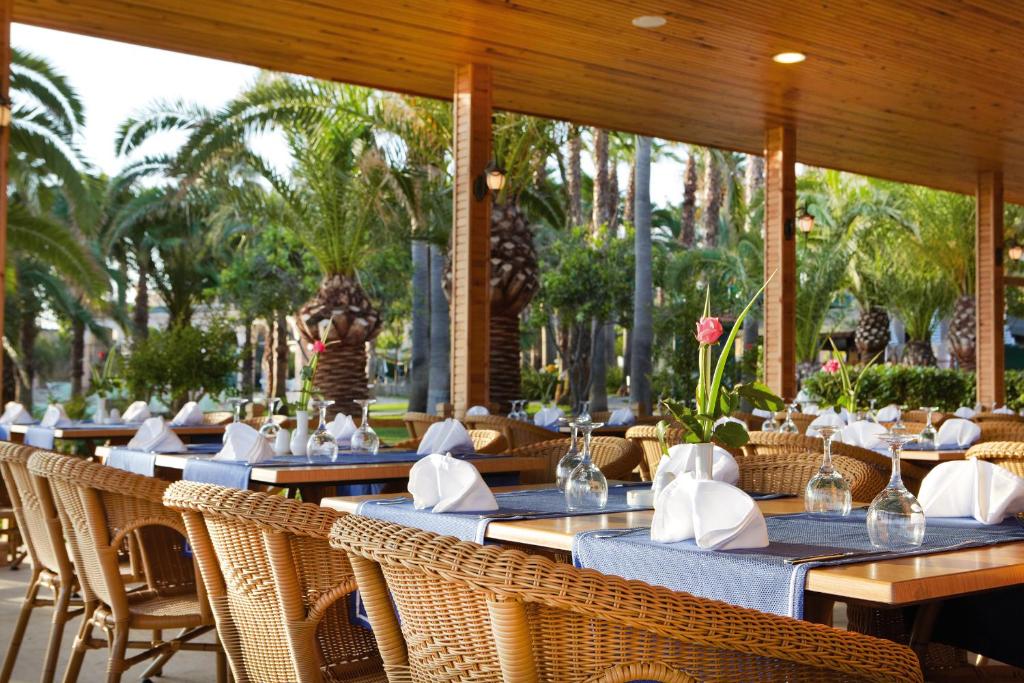 Meryan Hotel ēdināšanas zona ar palmām un eleganti klātiem galdiem