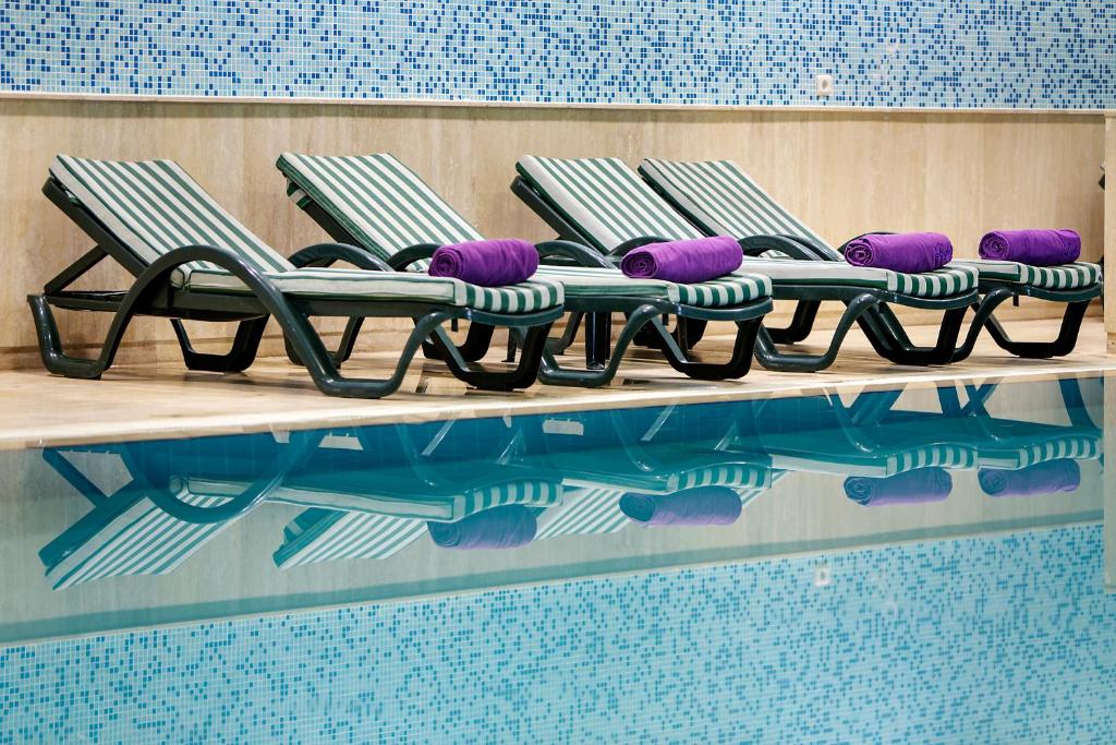 Meryan Hotel baseina atpūtas krēsli ar purpura dvieļiem