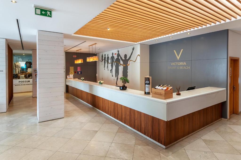 AP Victoria Sport & Beach Hotel reģistratūra ar modernu dizainu un sporta tematikas sienas dekoru.