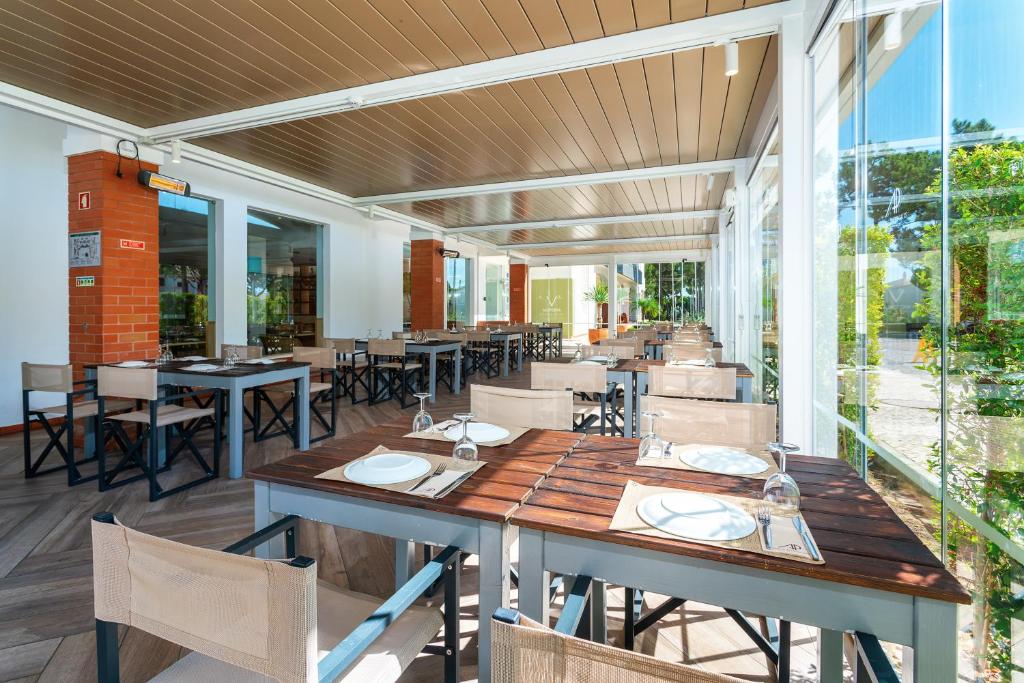 AP Victoria Sport & Beach Hotel restorāna terase ar koka galdiem un stikla sienām gaišā atmosfērā.
