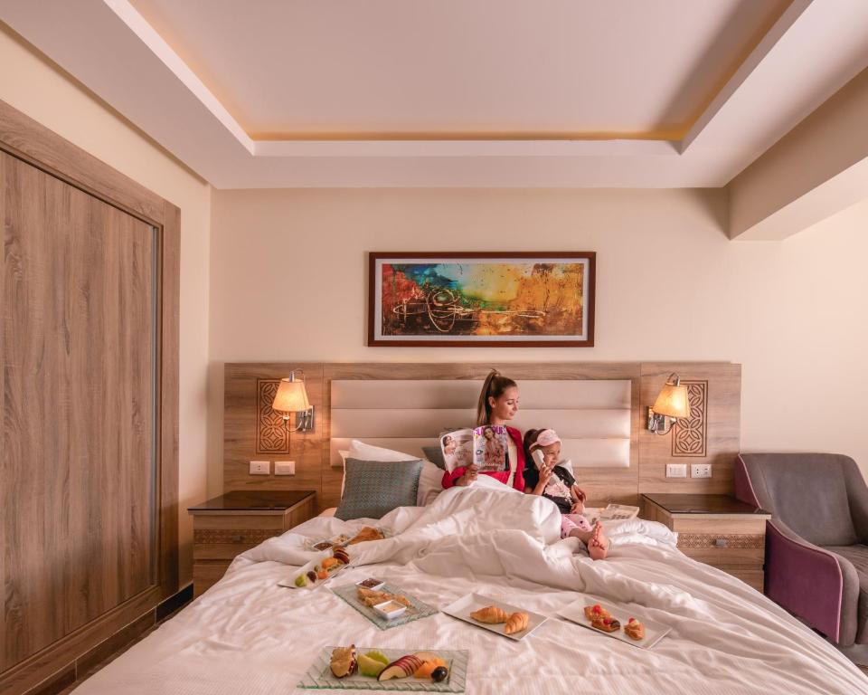 Sieviete un bērns pie gultas Pickalbatros Dana Beach Resort, baudot brokastis.