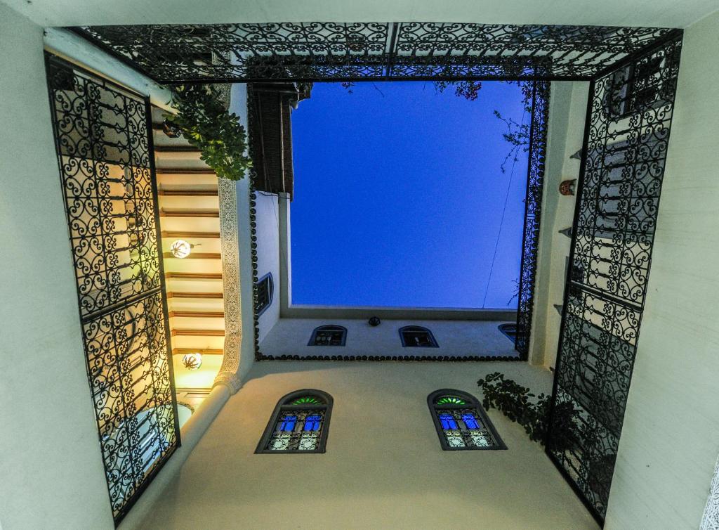 Skats uz debesīm no pagalma, kur redzami dekoratīvi metāla žogi un krāsaini logi, kas piešķir unikālu atmosfēru.