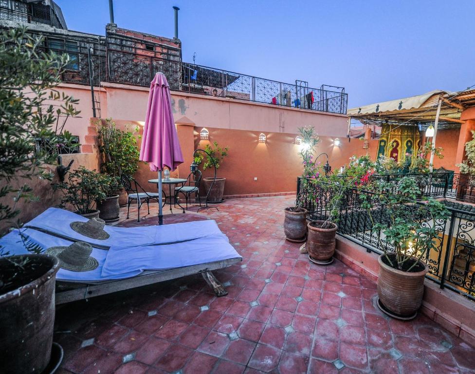 Terases telpa ar sēdvietām, sauļošanās krēsliem un rozā saulesvārdu, ko ieskauj ziedi un augi. Pēcpusdienas gaisma rada relaksējošu atmosfēru.