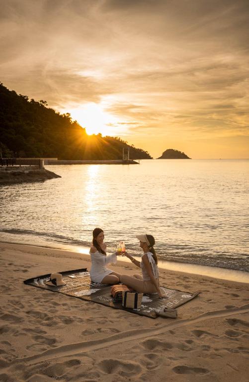 Divas draudzenes svin saulrietu pie pludmales The Aiyapura Koh Chang Resort.