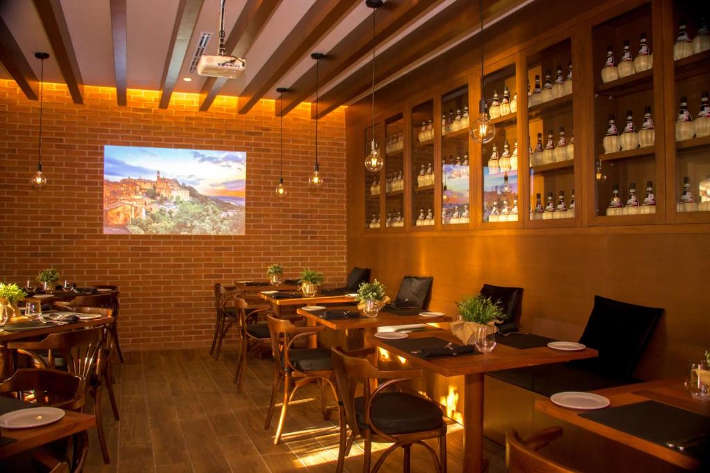 Mūsdienīgs restorāns ar siltu koka apdari un izgaismotiem interjera elementiem, kas rada patīkamu atmosfēru. Uz sienas ir projekcija ar ainavu, bet uz plauktiem redzamas pudeles, kas piešķir vietai unikālu šarmu.