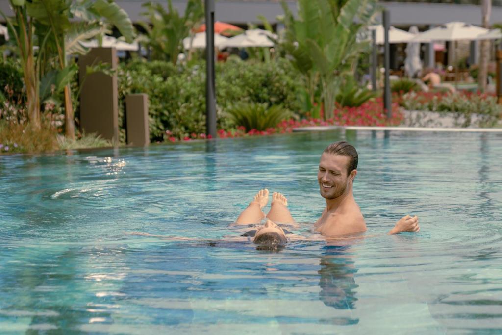Vīrietis un sieviete atpūšas baseinā pie LIU Resorts