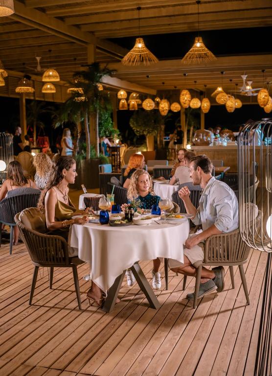 Trīs viesi baudot vakariņas āra restorānā LIU Resorts