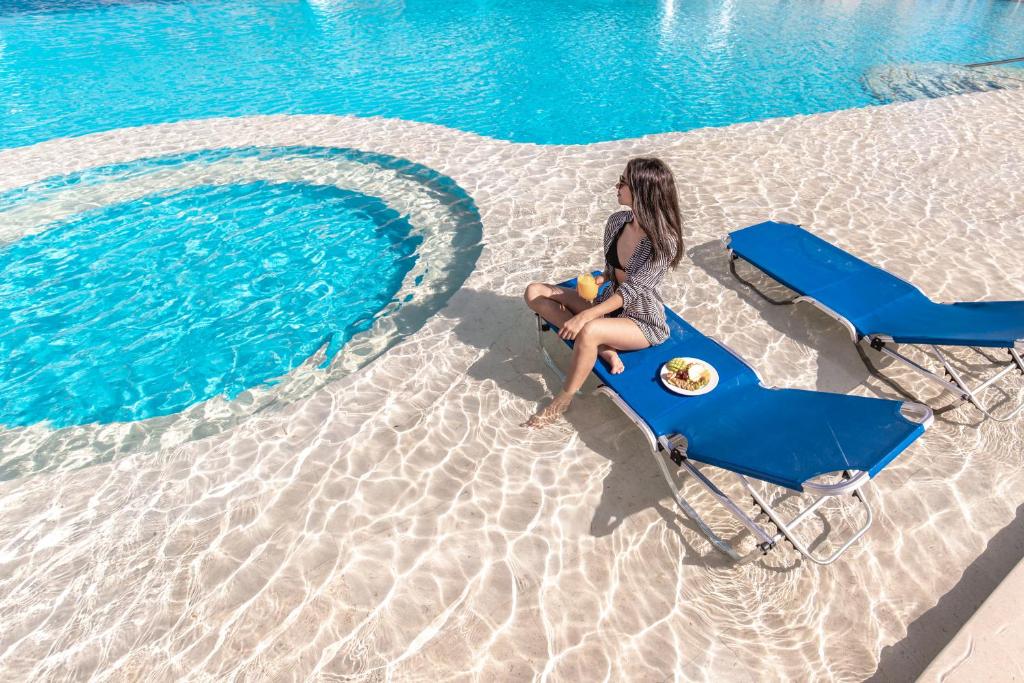 Sieviete atpūšas uz sauļošanās krēsla pie baseina Albatros Aqua Blu Resort.