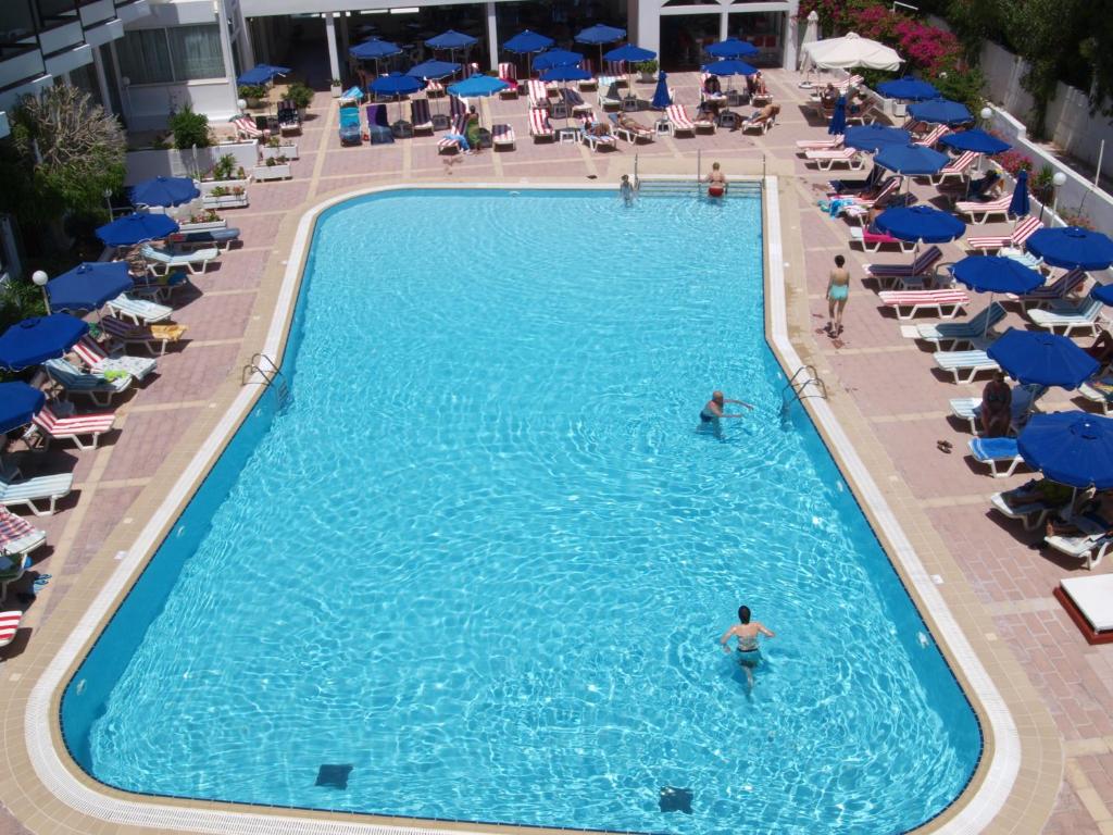 Baseins Belair Beach viesnīcā ar zilu ūdeni un saulessargiem piekrastē.