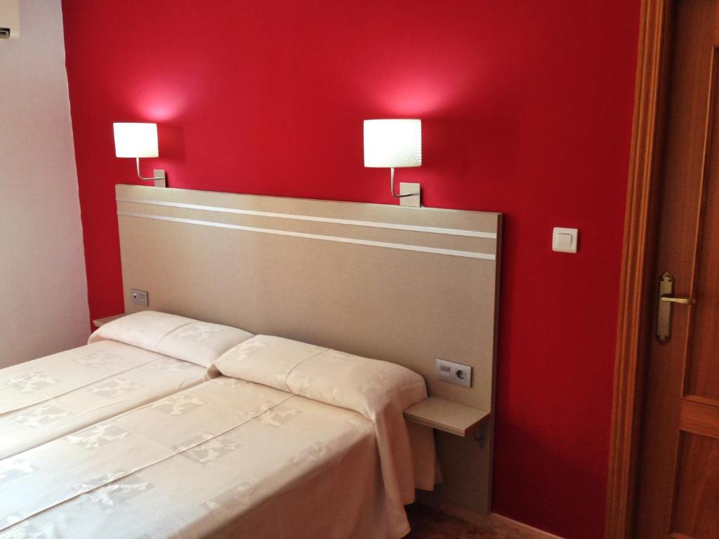 Mūsdienīgs guļamistabas interjers ar sarkanu sienu, divām gultām un stilizētām lampām pie galvas klāja.
