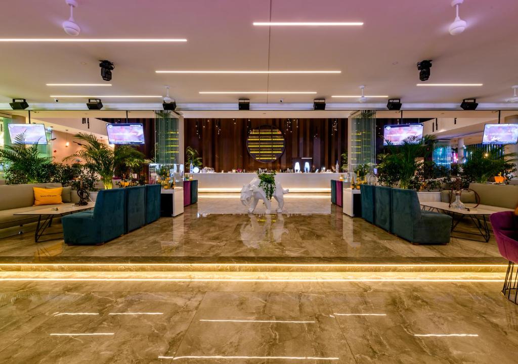 Mūsdienīgs bārs ar elegantu interjeru, stilīgiem dīvāniem un apzaļumotu vidi. Gaiša marmora grīda un LED apgaismojums rada patīkamu atmosfēru.