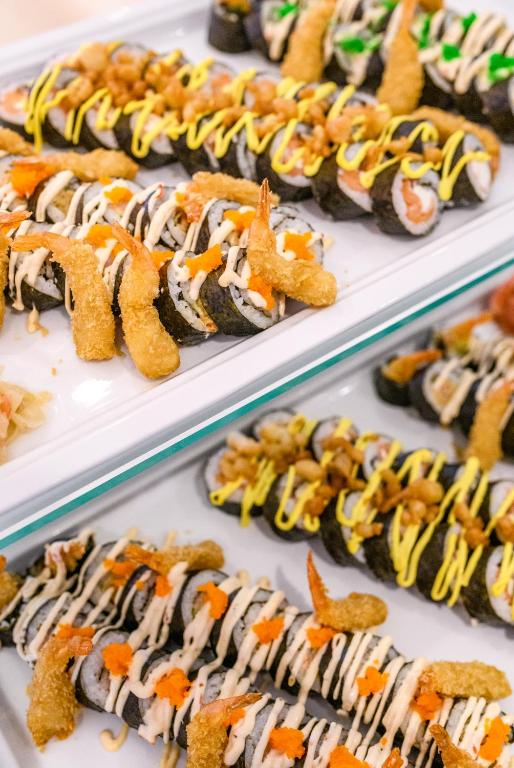 Svaigu sushi uzkodas, kas pasniegta uz balta šķīvja, ar garnelēm, mērci un dārzeņiem. Krāsains un pievilcīgs ēdiens, kas aicina baudīt.