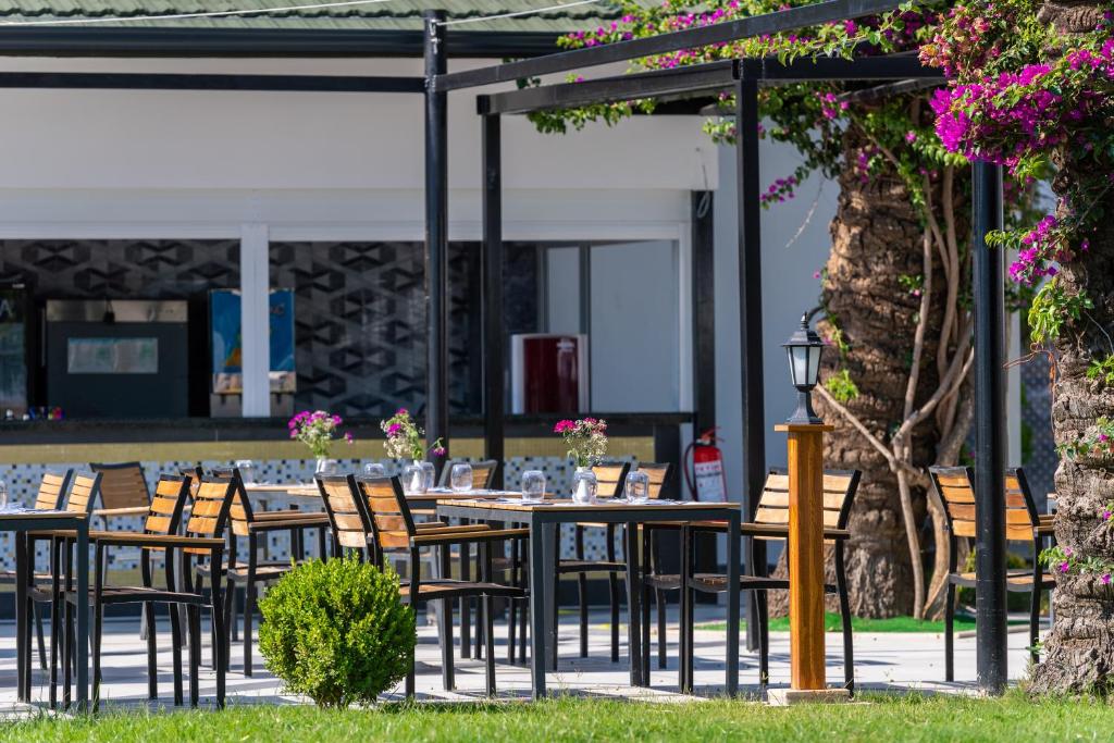 Āra ēdamzona pie Sealife Kemer Resort Hotel ar ziediem un koku ēnu.