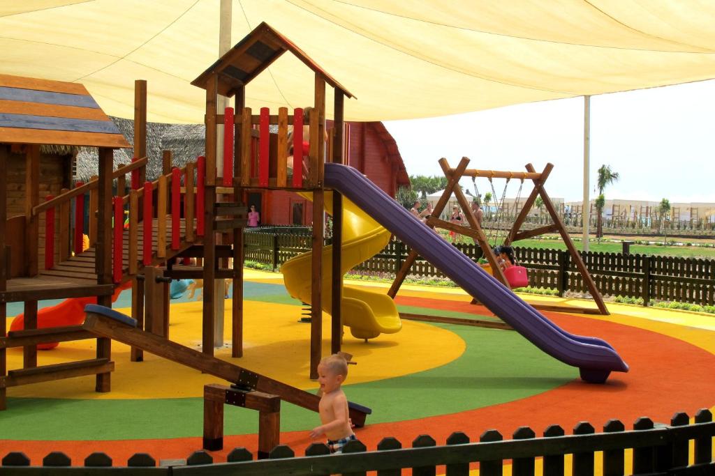 Bērnu rotaļu laukums pie Aska Lara Resort & Spa ar slidkalniņu un šūpolēm.