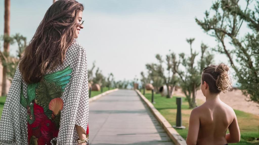 Māte un bērns pastaigājas pa gleznainu promenādi pie LIU Resorts.