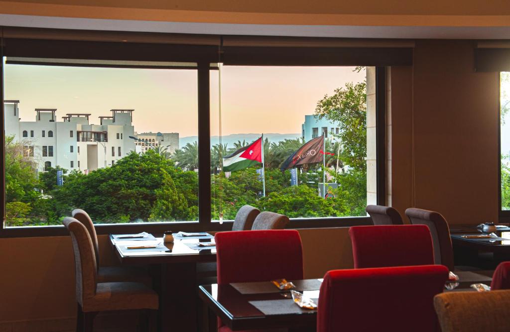 Restorāna interjers ar skatu uz ārpusi, kur redzami koki un ēkas, kā arī karogi.