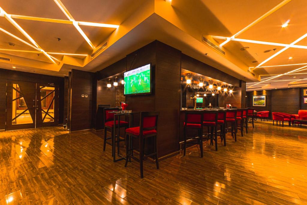 Mūsdienīgs bārs ar sarkanām krēslām un elegantu apgaismojumu, kurā ir liels televizors sporta pārraižu skatīšanai. Plašs un gaumīgs interjers, kas radīts patīkamai atpūtai.