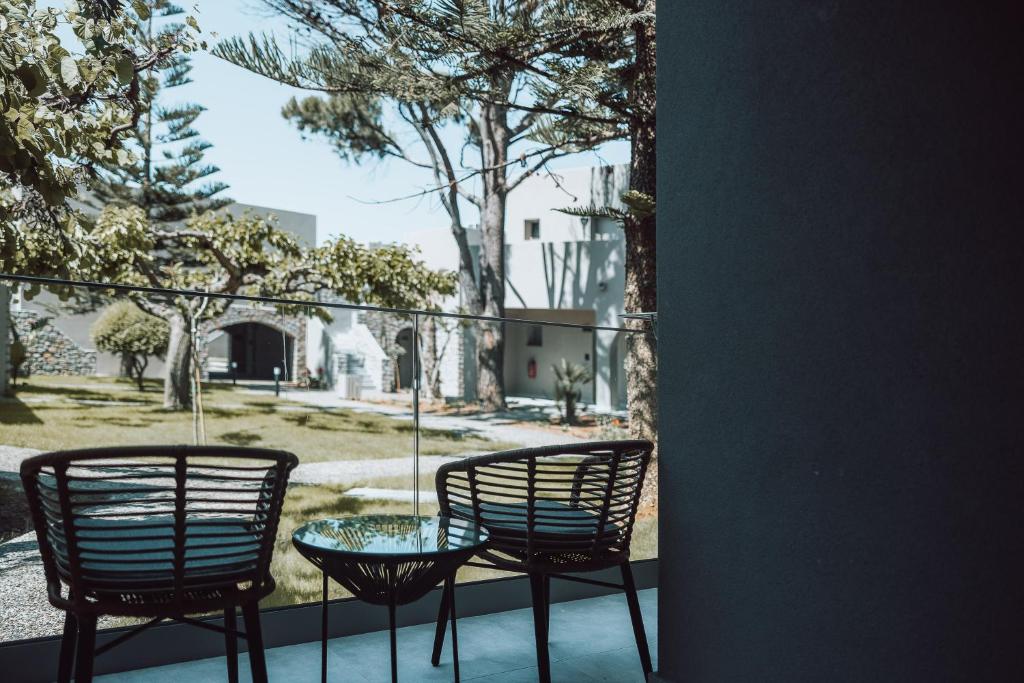 Mūsdienīgs balkons ar divām krēslām un galdiņu, skats uz zaļo dārzu un ēkām fonā. Ideāla vieta relaksācijai un baudīšanai.