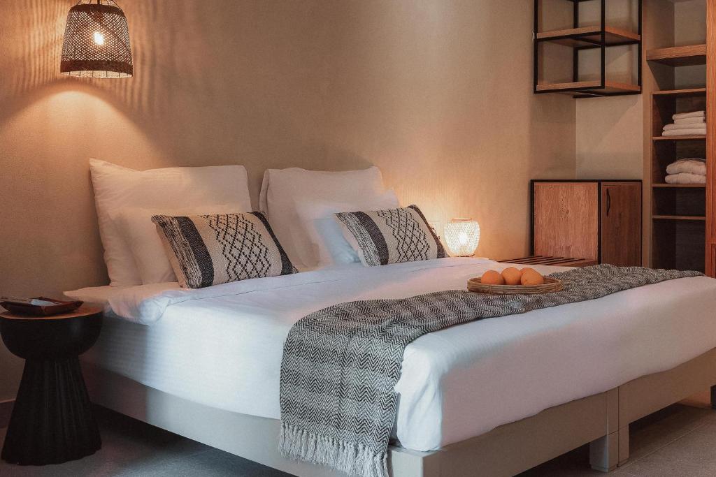 Mūsdienīga guļamistaba ar ērtu divguļamo gultu, dekoratīvām spilveniem un siltu apgaismojumu, kas rada mājīgu atmosfēru. Blakus gultai ir neliels galdiņš un dekoratīvi elementi.