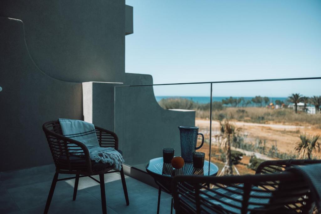 Mūsdienīga balkona zona ar skatu uz jūru, kurā ir divas krēslus, galdiņš un dzērienu trauki. Ideāla vieta atpūtai un relaksācijai.